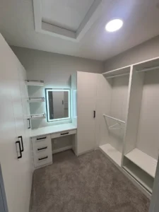 Completed custom walk-in closet with built-in cabinetry, makeup desk and illuminated mirror.