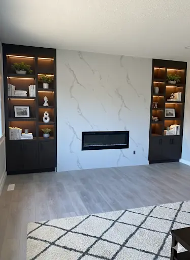 Completed fireplace wall with illuminated built-in shelving and lower cabinetry.