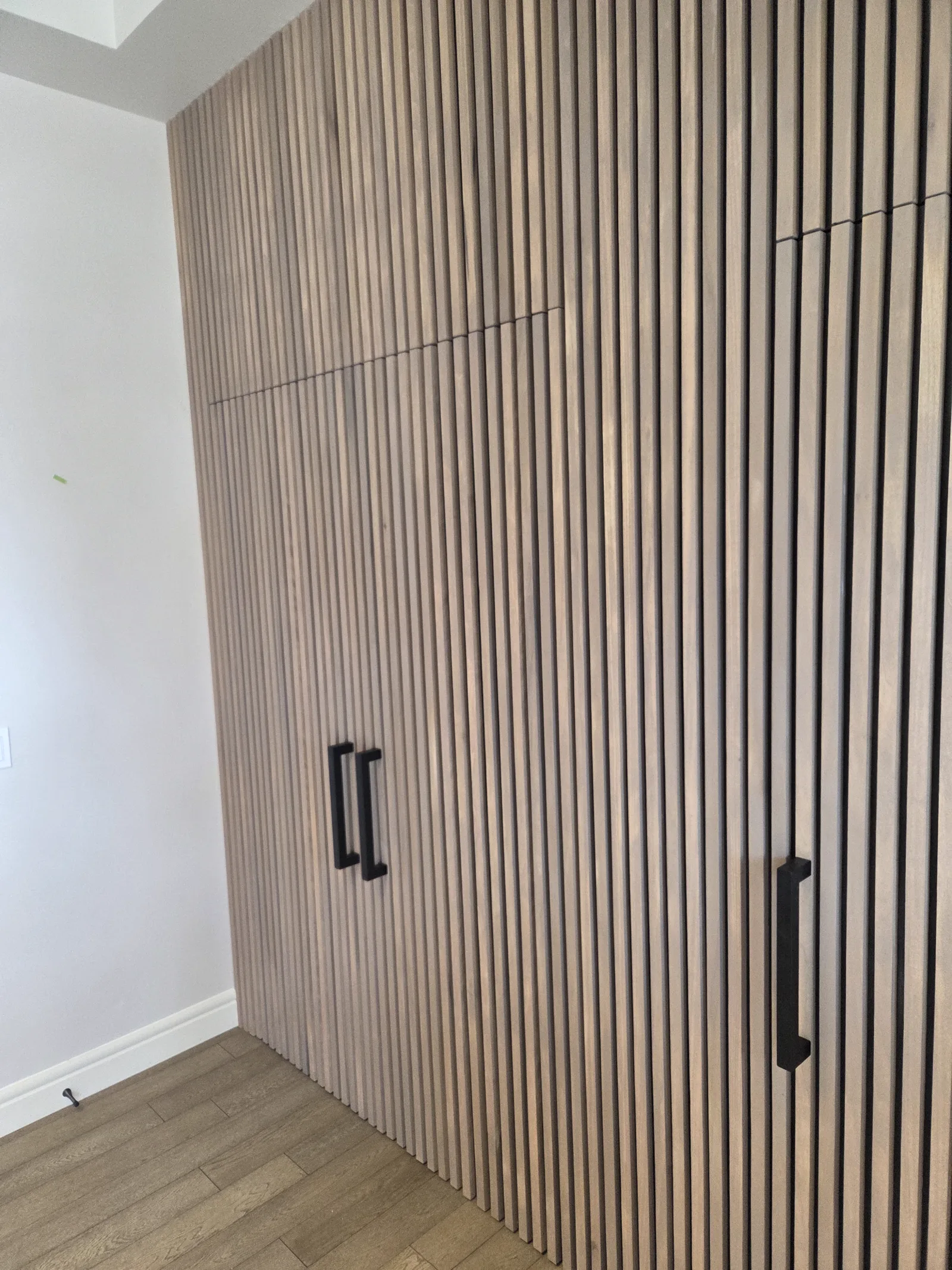 Custom hidden doors integrated into a wood slat wall in a Calgary home