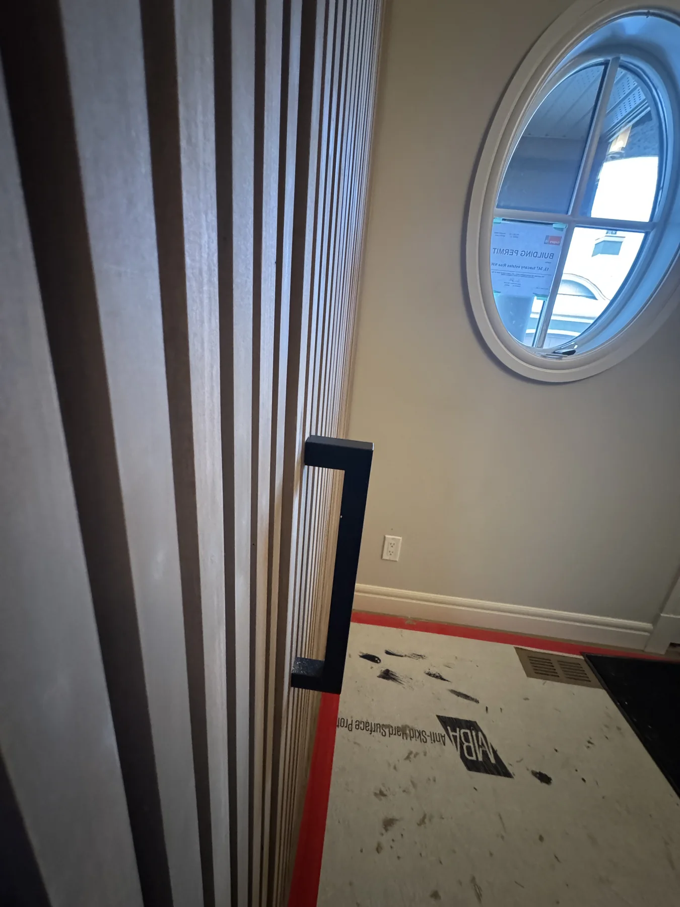 Black pull integrated into a finished slat-panel hidden door